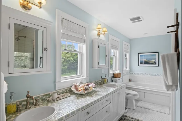 a bathroom with a granite countertop sink vanity mirror and a bathtub