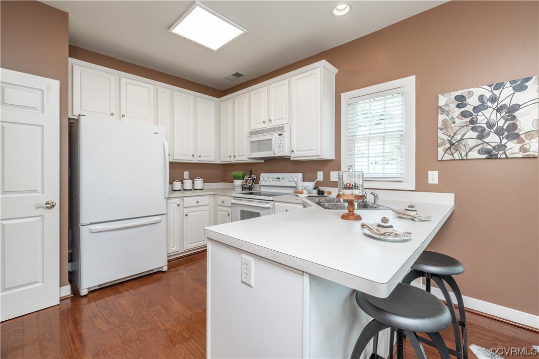2152 Magnolia Grove Way, Unit 2152 Midlothian, VA 23113 - Photo 12 of 38 a kitchen with a sink a stove a refrigerator and white cabinets with wooden floor