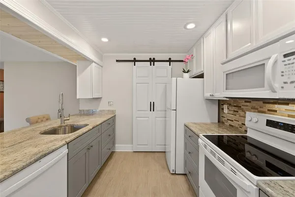 a kitchen with granite countertop a sink stove and refrigerator