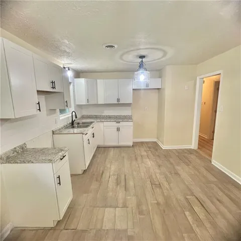 a large white kitchen with kitchen island a sink stainless steel appliances and cabinets