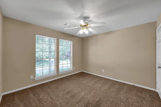an empty room with windows and ceiling fan