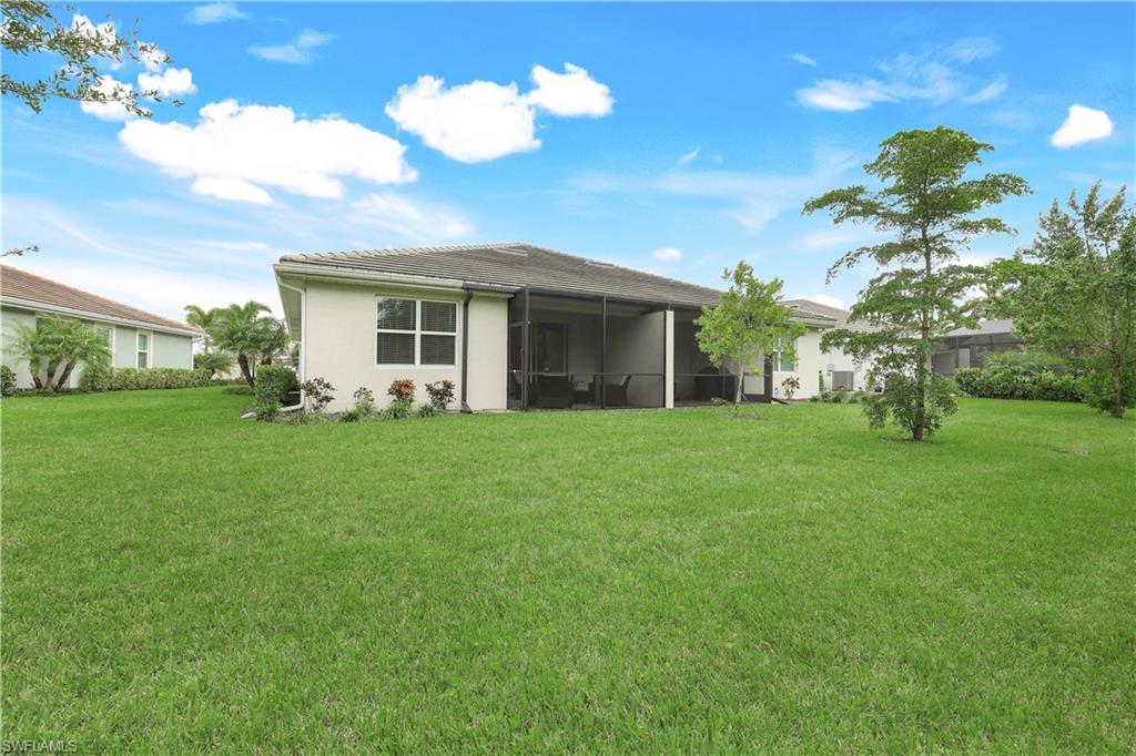 14551 Edgewater Circle Naples, FL 34114 - Photo 23 of 26 Rear view of house with a lawn and a sunroom