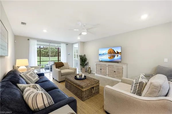 a living room with furniture a flat screen tv and a large window