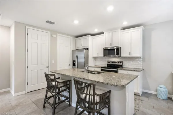 a kitchen with granite countertop a table chairs microwave and refrigerator