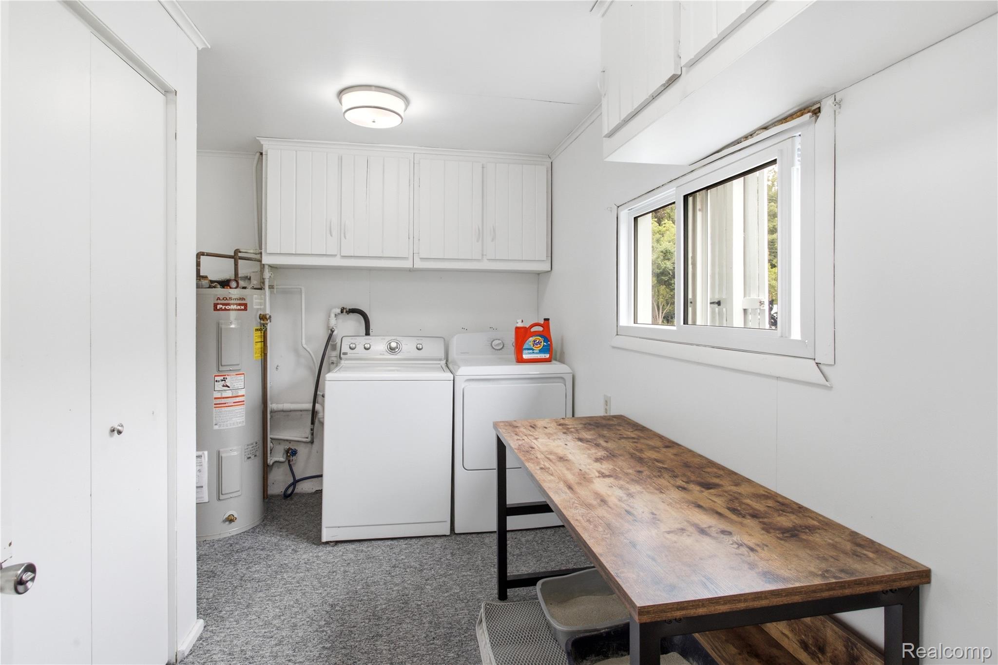 4945 Miller Road Ann Arbor, MI 48103 - Photo 19 of 42 Laundry area featuring overhead cabinetry, a water heater, and a sliding window