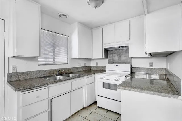 a kitchen with granite countertop white cabinets and white appliances