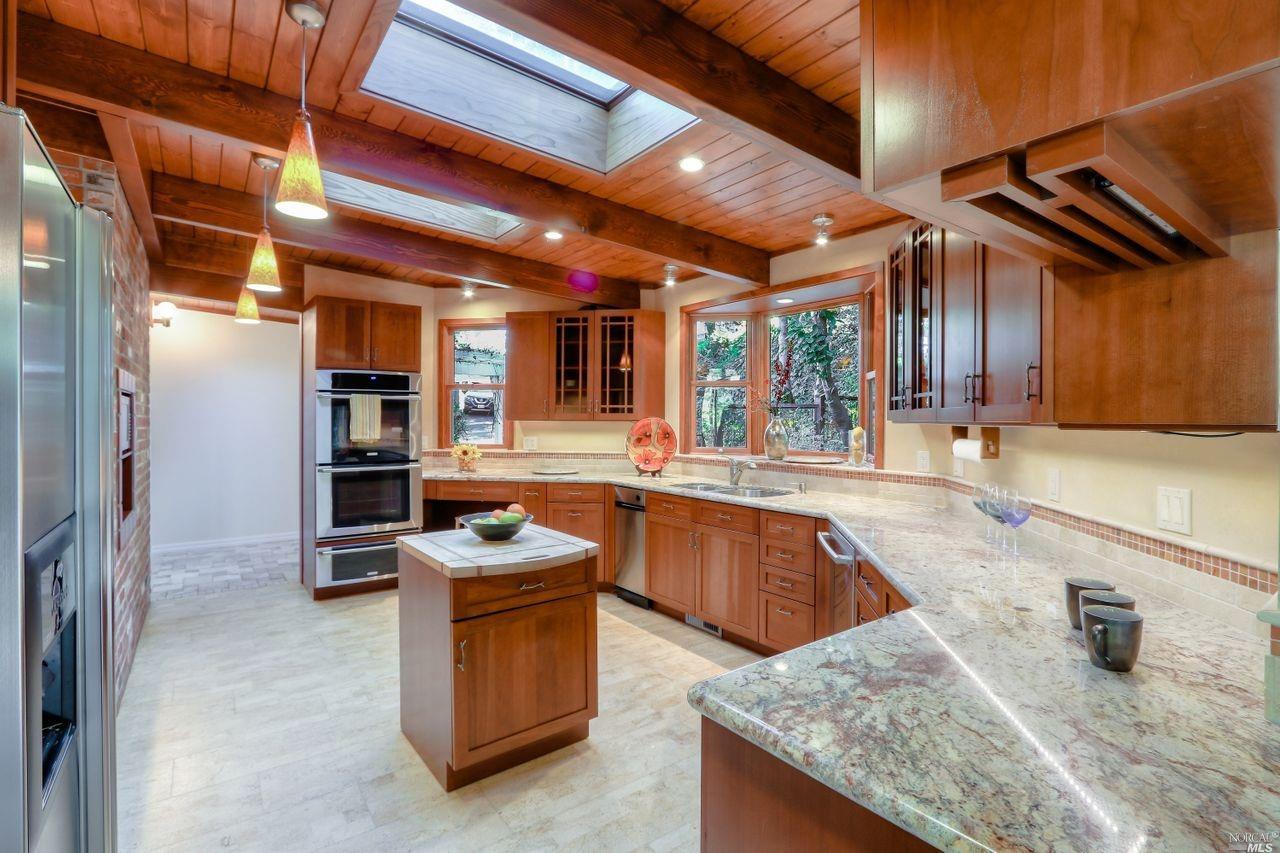 a kitchen with granite countertop kitchen island stainless steel appliances a stove a sink and a refrigerator