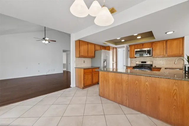 a large kitchen with kitchen island granite countertop a stove a sink a window and stainless steel appliances