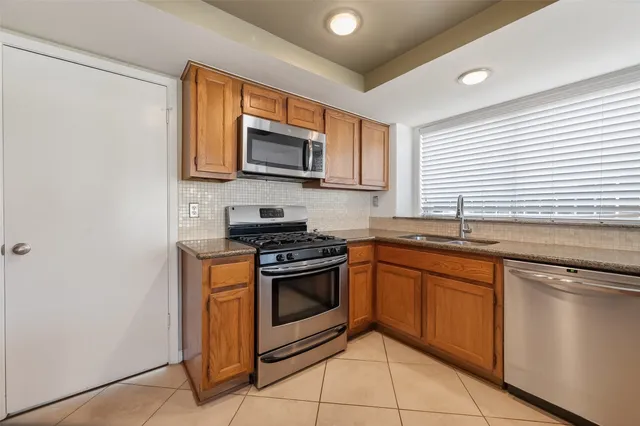 a kitchen with stainless steel appliances granite countertop a stove top oven a sink and a microwave