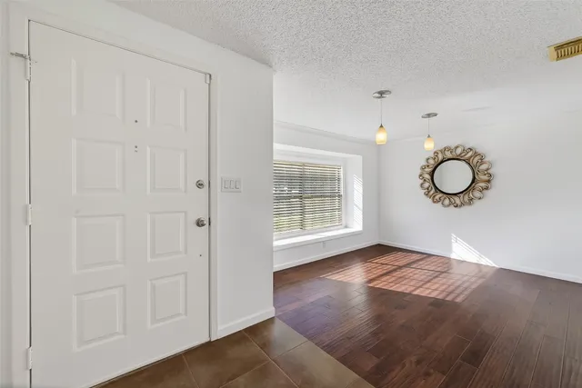 an empty room with wooden floor cabinet and windows
