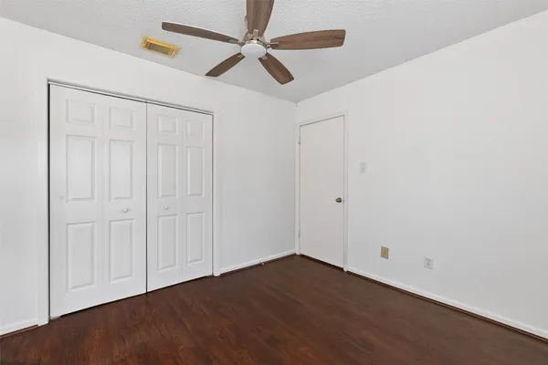 an empty room with wooden floor ceiling fan