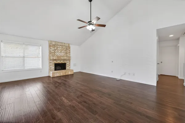 an empty room with wooden floor chandelier and windows