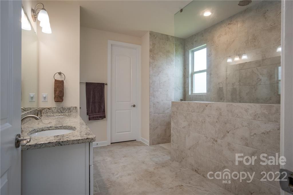 1213 Independence Street Tega Cay, SC 29708 - Photo 21 of 35 a bathroom with a granite countertop sink a mirror and a shower