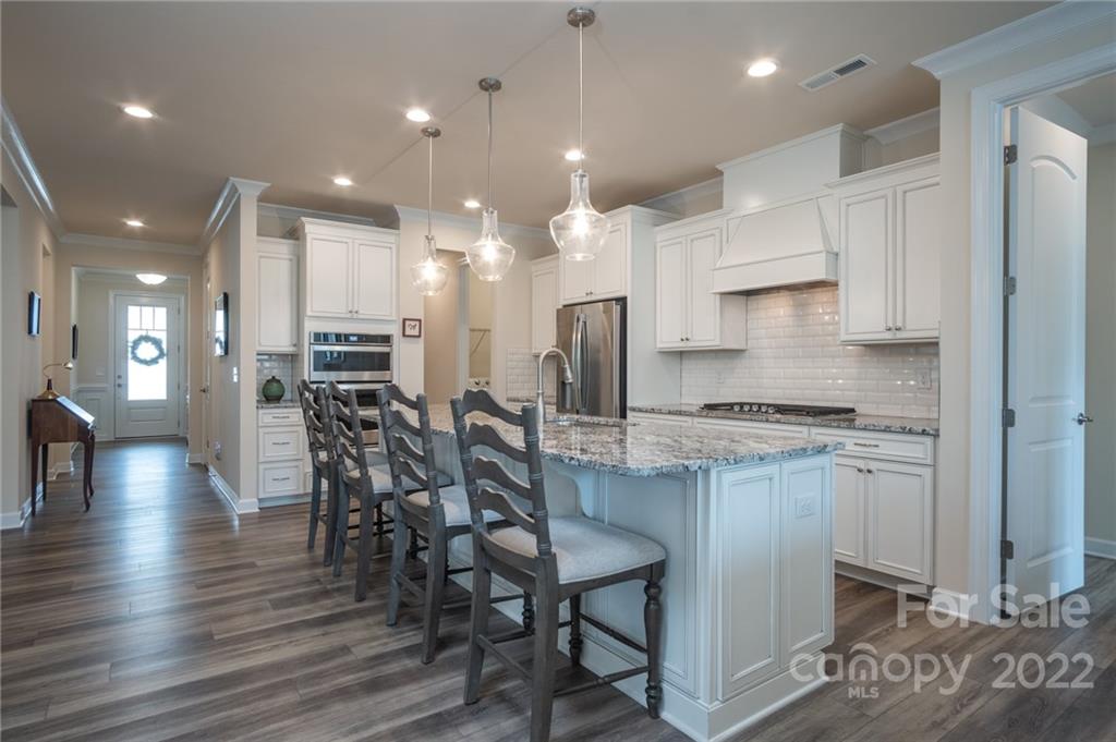1213 Independence Street Tega Cay, SC 29708 - Photo 8 of 35 a kitchen with stainless steel appliances kitchen island granite countertop a stove a sink a refrigerator and white cabinets with wooden floor