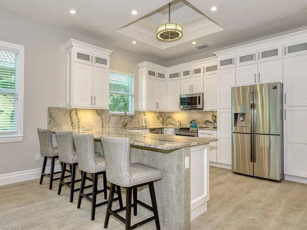 a kitchen with stainless steel appliances granite countertop a table chairs sink refrigerator and microwave
