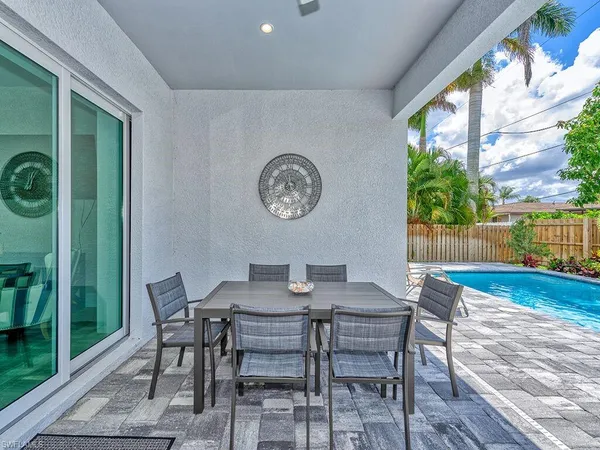 a backyard of a house with table and chairs plants and large trees