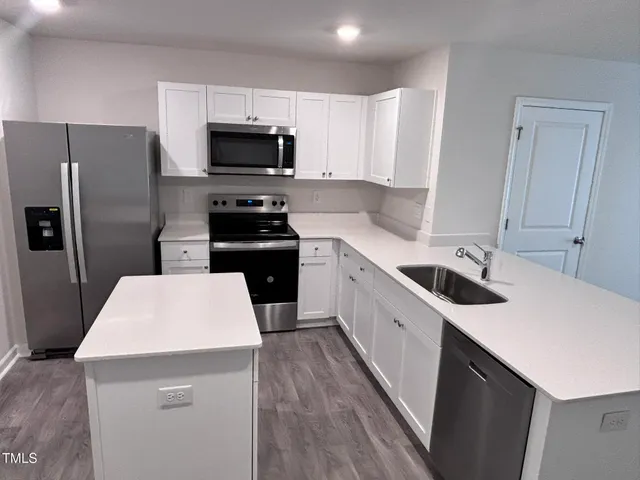 a kitchen with a sink a microwave a refrigerator and cabinets