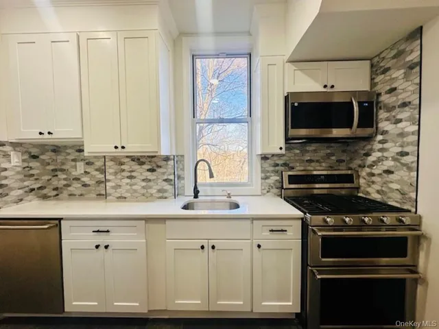a kitchen with stainless steel appliances white cabinets and a stove top oven