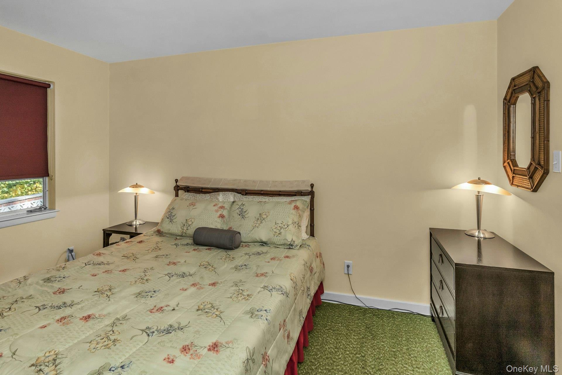 31 Knolls Lane Manhasset, NY 11030 - Photo 16 of 27 a bedroom with a bed a mirror and lamp