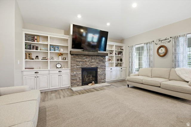 3123 East Riverdale Road Preston, ID 83263 - Photo 7 of 52 Family Room - Living space featuring a stone-clad fireplace with a wood mantel, built-in white cabinetry with open shelving, recessed lighting, and large windows