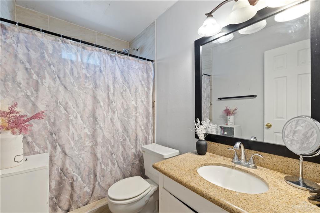 320 Violet Avenue Mission, TX 78574 - Photo 7 of 14 a bathroom with a granite countertop sink vanity mirror and toilet