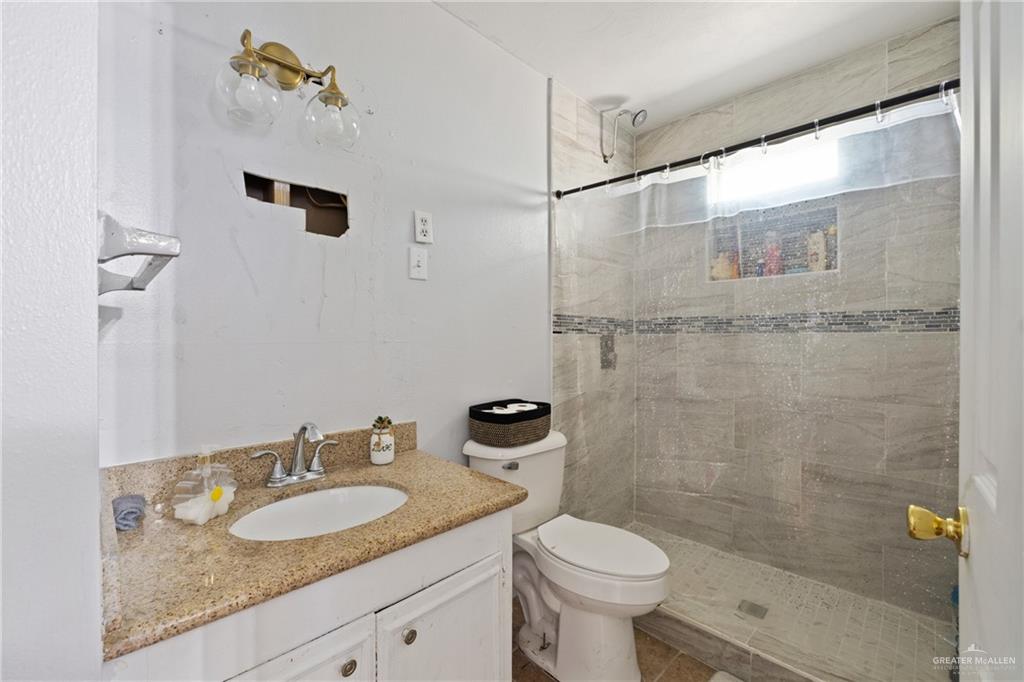320 Violet Avenue Mission, TX 78574 - Photo 9 of 14 a bathroom with a granite countertop sink a toilet and shower