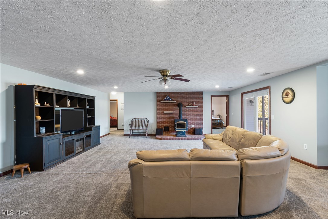 3393 Friendsville Road Wooster, OH 44691 - Photo 23 of 34 Living room with a textured ceiling, recessed lighting, light colored carpet, baseboards, and a wood stove