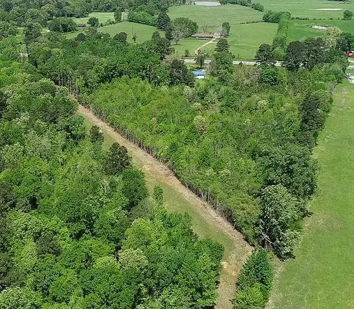 an aerial view of residential house with outdoor space and trees all around