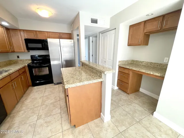 a kitchen with granite countertop a refrigerator and a stove top oven