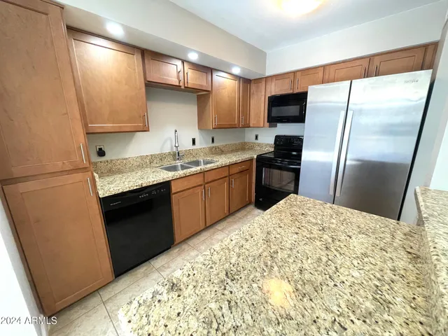 a kitchen with stainless steel appliances granite countertop a refrigerator sink and stove