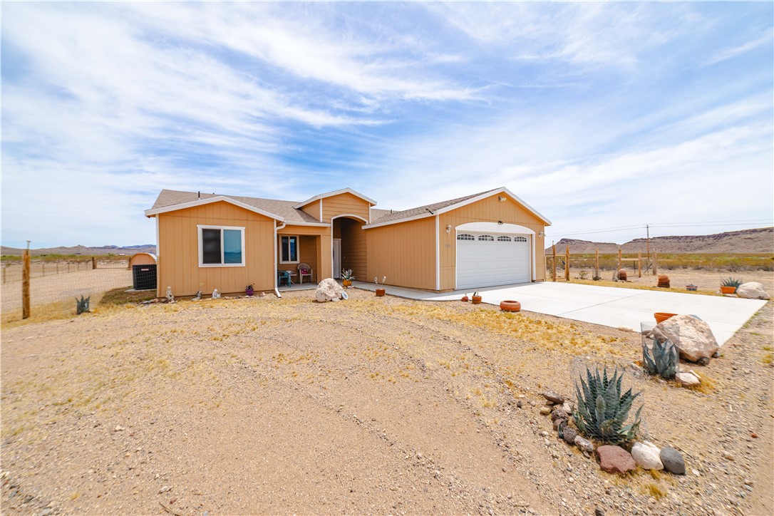 2948 Pinal Road Golden Valley, AZ 86413 - Photo 52 of 59 Single-story residence featuring a two-car garage with an arched panel door, a concrete driveway, a covered front entry, and a stucco exterior finish