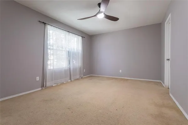 an empty room with chandelier fan and windows