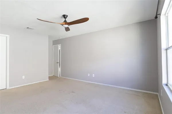 an empty room with a window and a ceiling fan