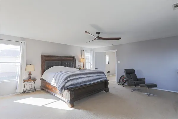 a spacious bedroom with a bed and chair