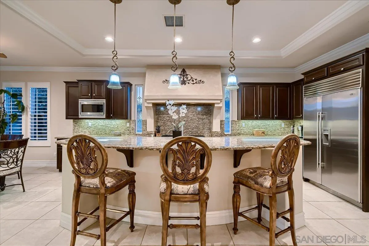 3349 Mendenaro Court Fallbrook, CA 92028 - Photo 12 of 34 a kitchen with stainless steel appliances granite countertop a stove a refrigerator a kitchen island a dining table and chairs with wooden floor