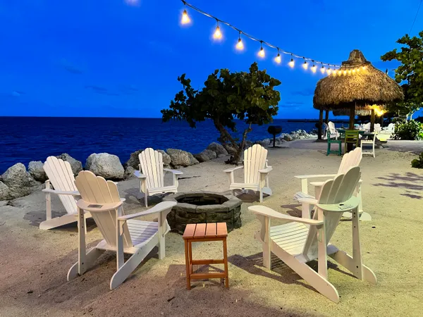 a view of patio with table and chairs under an umbrella with a barbeque