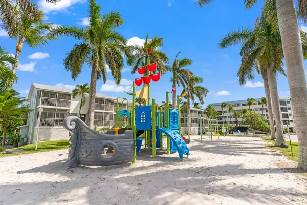 a view of a swimming pool with lawn chairs potted plants and palm trees