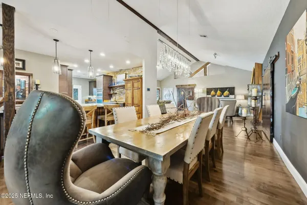 a kitchen with stainless steel appliances kitchen island granite countertop a table chairs and a wooden floor