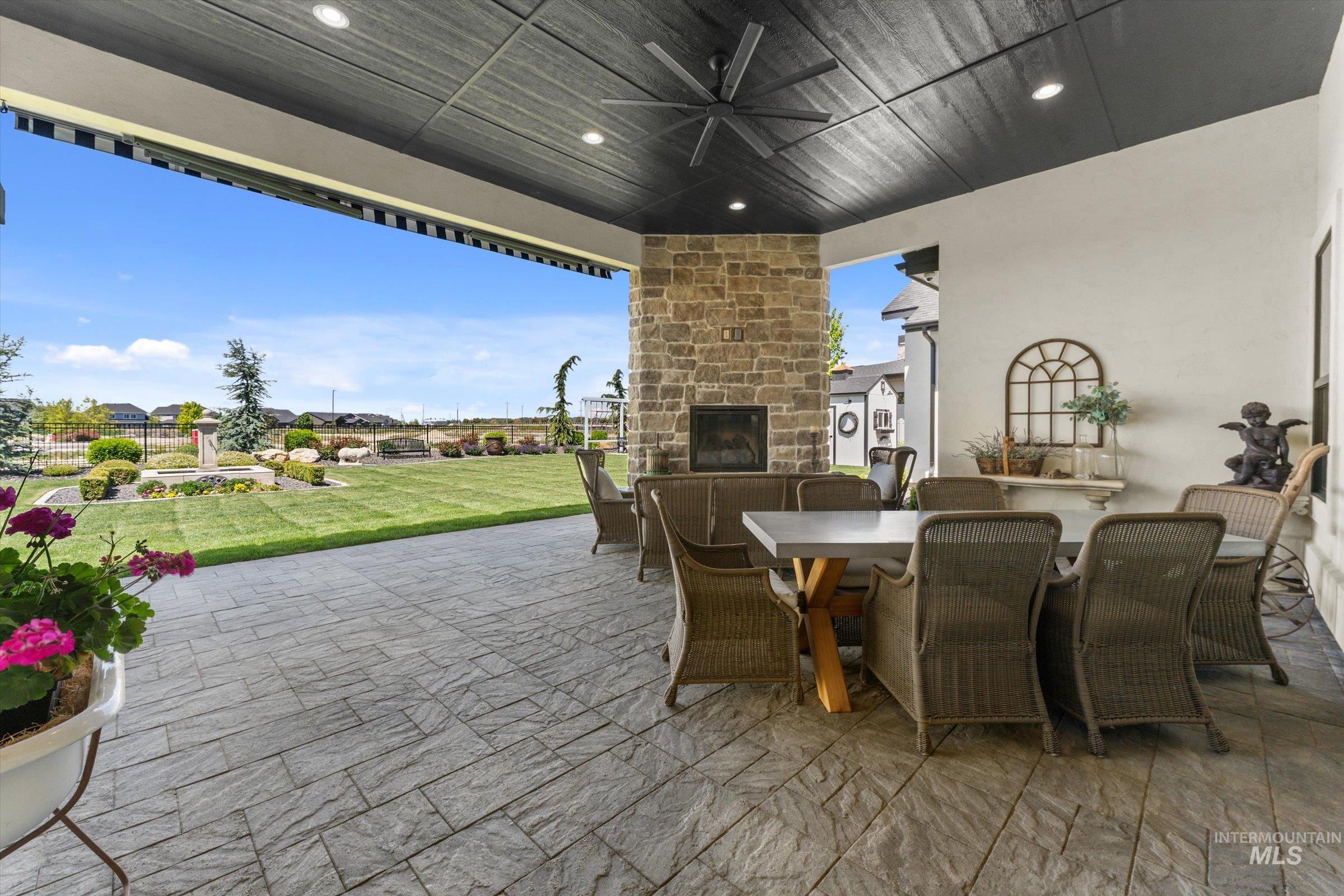 6585 South Pemberley Way Meridian, ID 83642 - Photo 40 of 43 Covered patio featuring textured paving stones, a stone-clad fireplace, and a ceiling fan