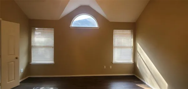 an empty room with wooden floor and a window