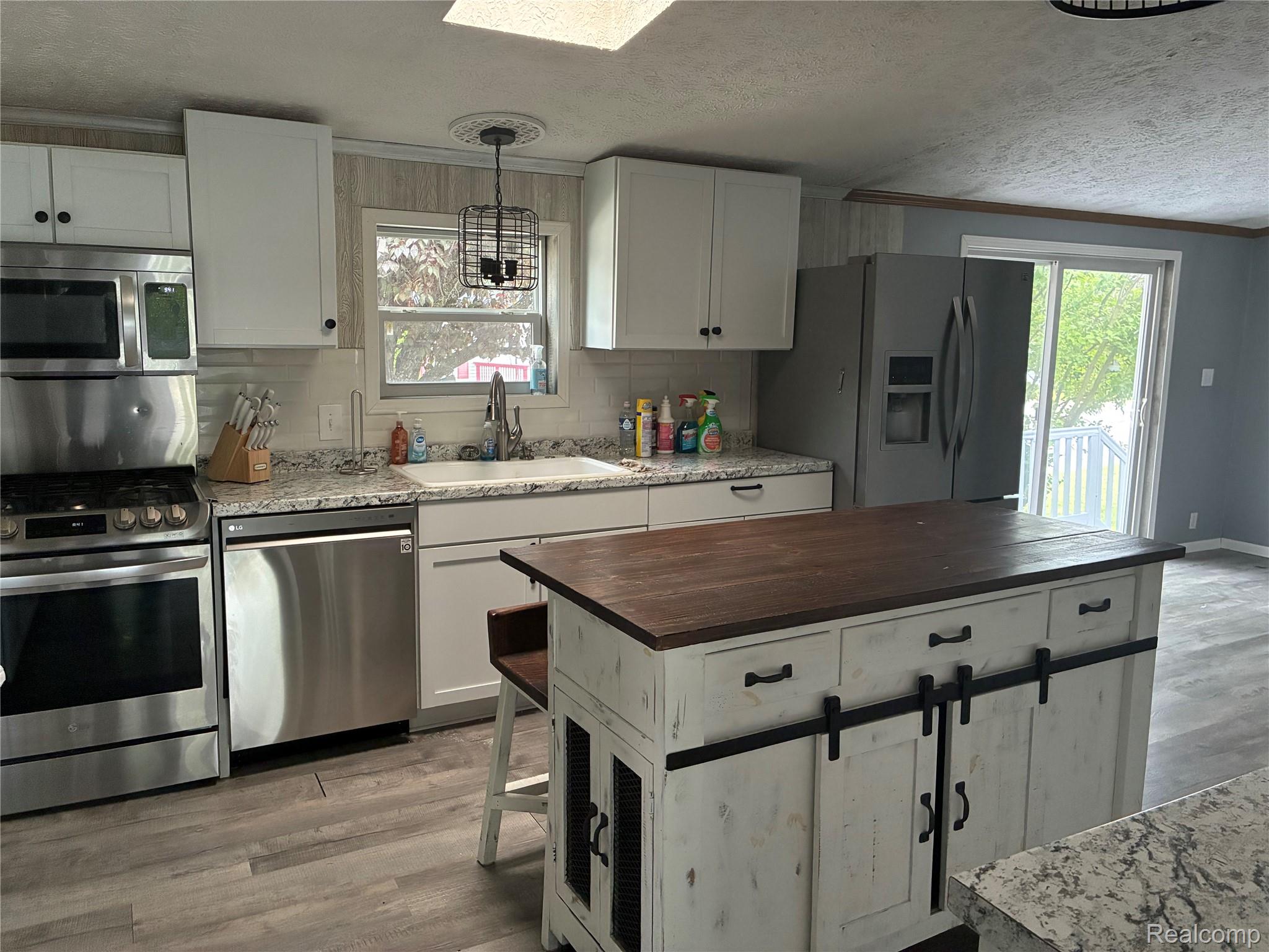 7364 Kings Court Alma, MI 48801 - Photo 10 of 16 Kitchen featuring a large island with a wood-finish countertop, white cabinetry, and stainless steel appliances