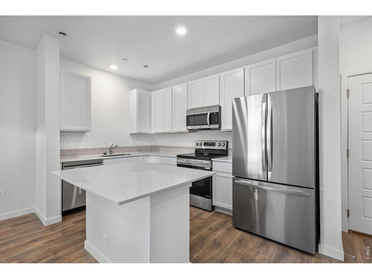 3905 Net Street Evans, CO 80620 - Photo 3 of 19 a kitchen with kitchen island a refrigerator sink and cabinets