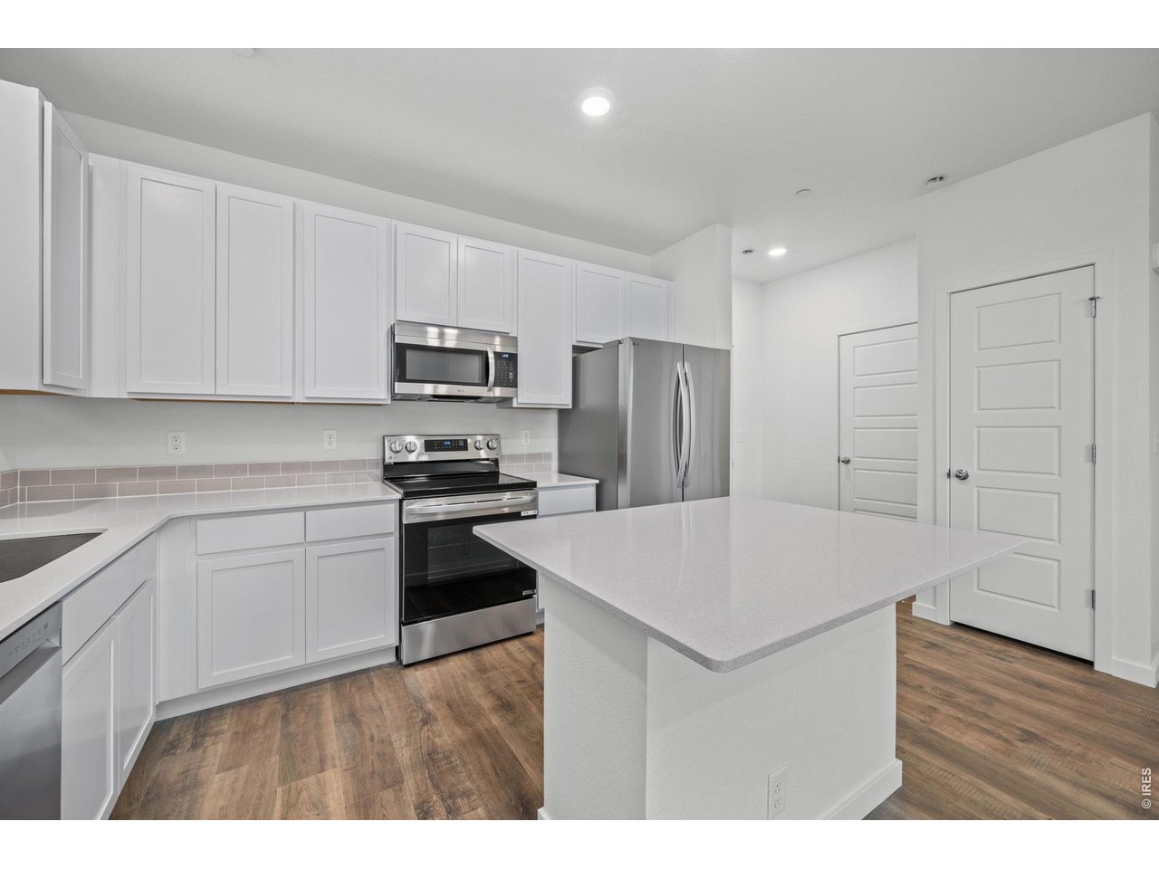 3905 Net Street Evans, CO 80620 - Photo 4 of 19 a kitchen with kitchen island a sink dishwasher a refrigerator and white cabinets