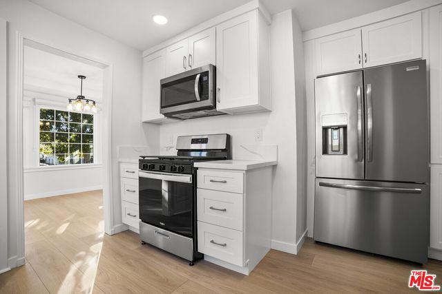 a kitchen with stainless steel appliances and wooden floor
