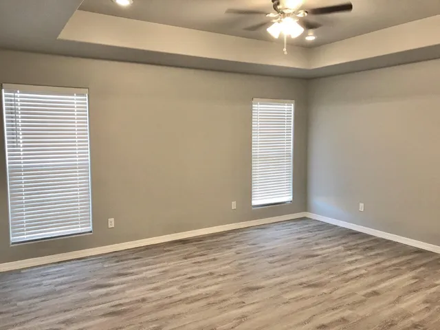 a view of an empty room with window and wooden floor