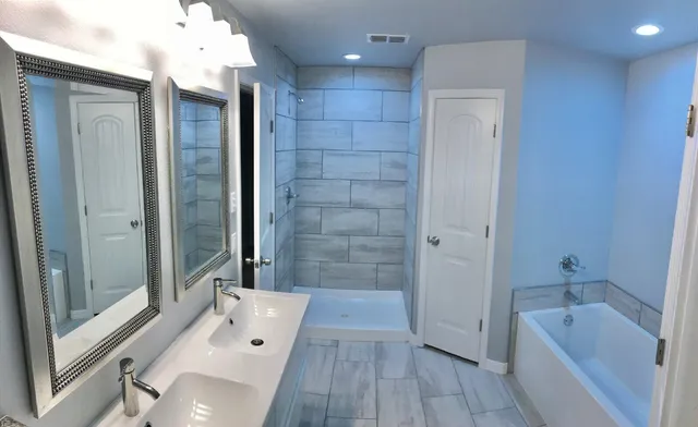 a bathroom with a tub shower and sink