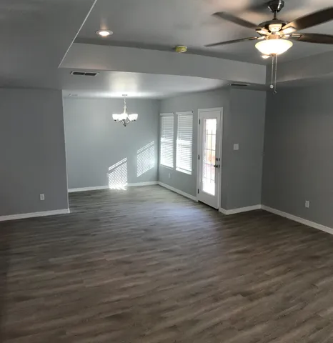 a view of an empty room with wooden floor and a ceiling fan