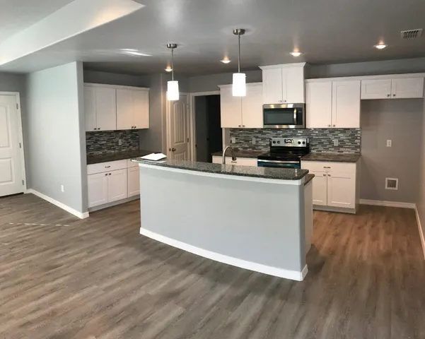 a kitchen with stainless steel appliances kitchen island granite countertop a stove top oven a sink and a microwave