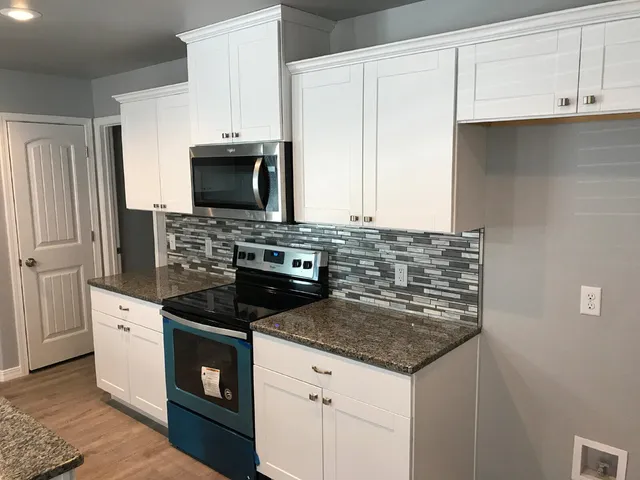 a kitchen with granite countertop a stove sink and refrigerator