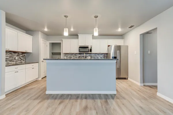 an empty room with wooden floor chandelier fan and windows